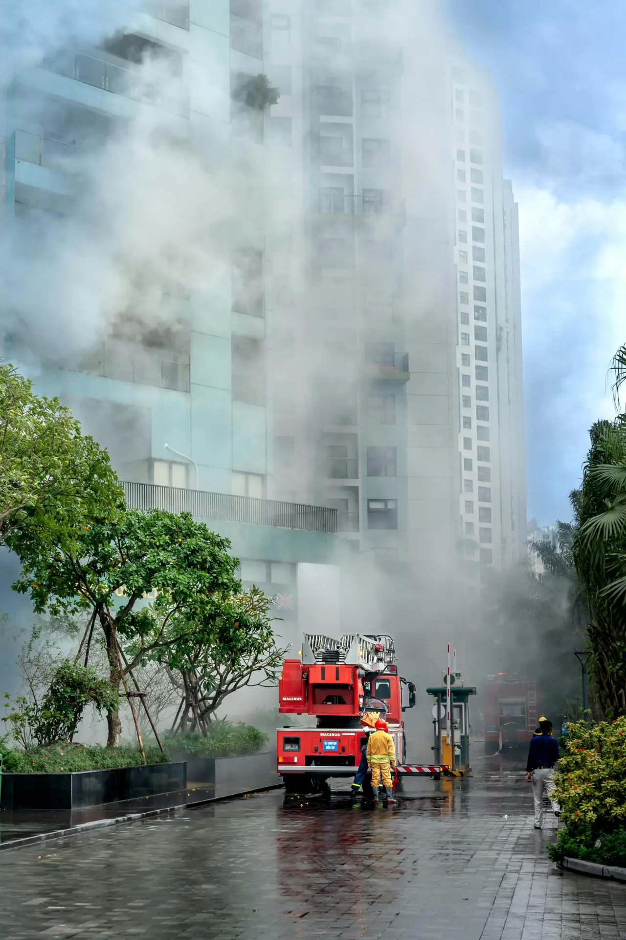 Firefighters combating a building fire with heavy smoke and fire truck in an urban setting.